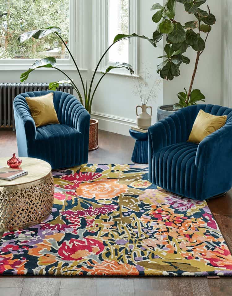 Vibrant Sanguine Rug Aubergine in stylish living room with blue velvet chairs.