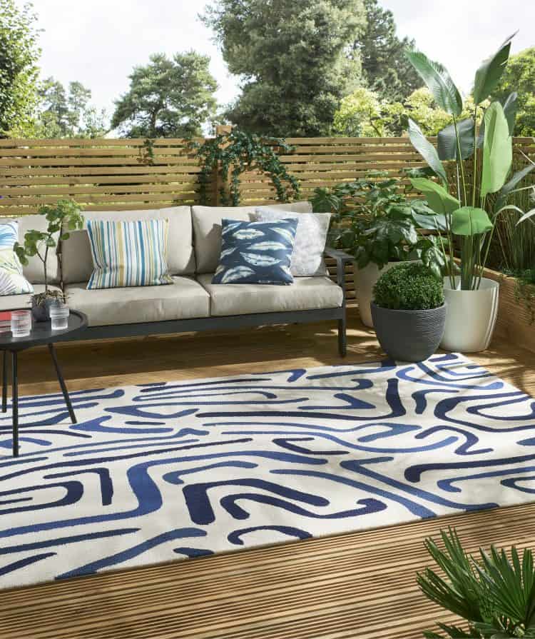 Stylish outdoor rug with blue abstract design on wooden deck.