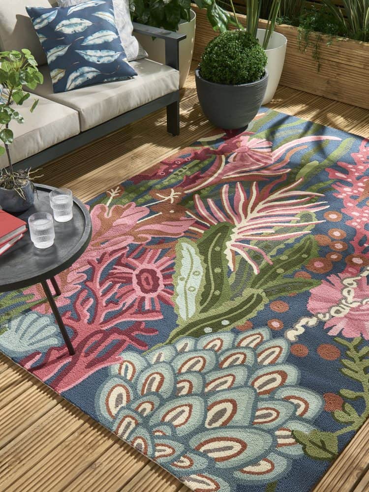 Vibrant tropical outdoor rug with pink, green, and blue foliage and coral patterns.