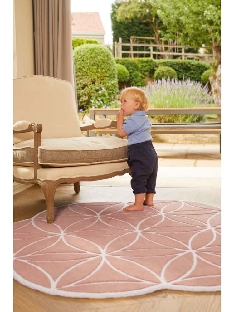 Child standing on a pink Bloom Rug Blush in a bright living room.