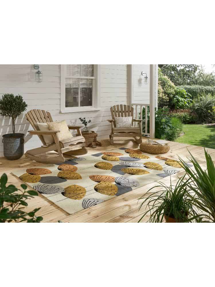 Indoor outdoor rug with dandelion clock design in a garden setting.
