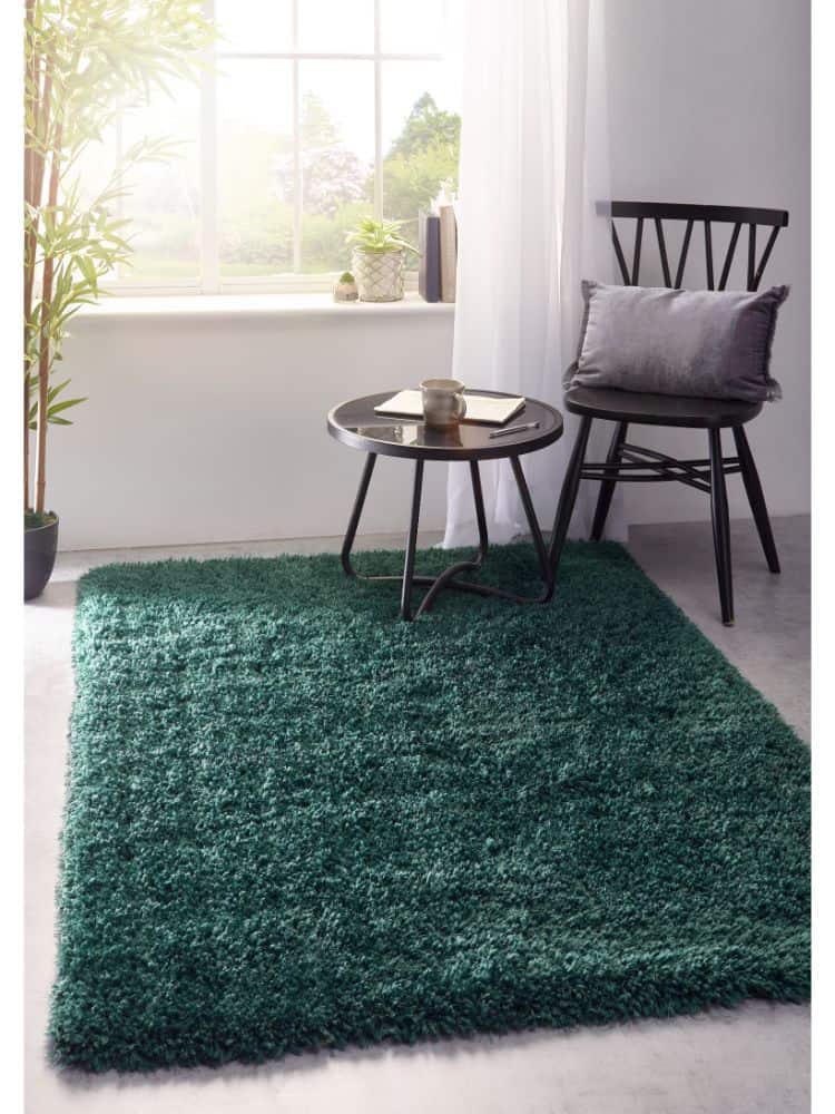 Forest green shaggy rug in a bright room with a black chair and small table.