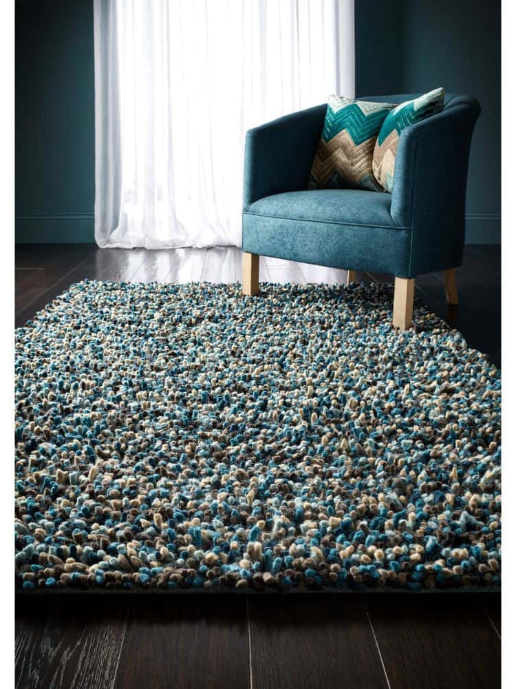 Blue shaggy rug in a modern living room with a teal armchair.