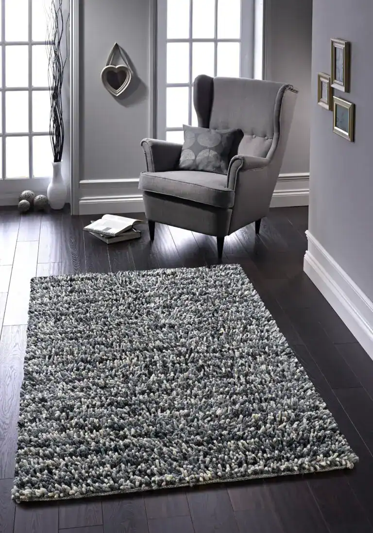 Grey shaggy rug in a modern living room with armchair and decor.