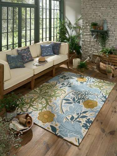 Colourful floral outdoor rug in a bright living room with plants and a cream sofa.