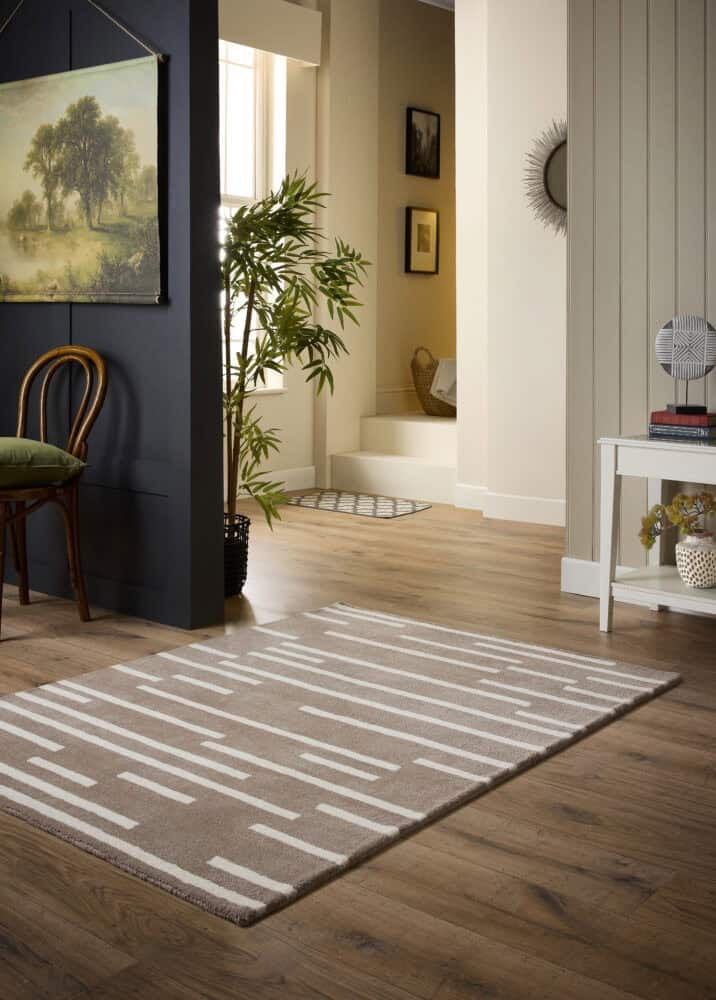Beige broken stripe rug in modern living room with wooden flooring.