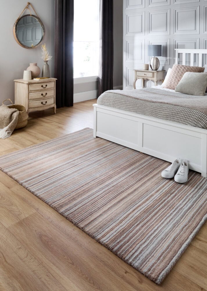 Beige striped rug in a modern bedroom with white furniture and wooden flooring.