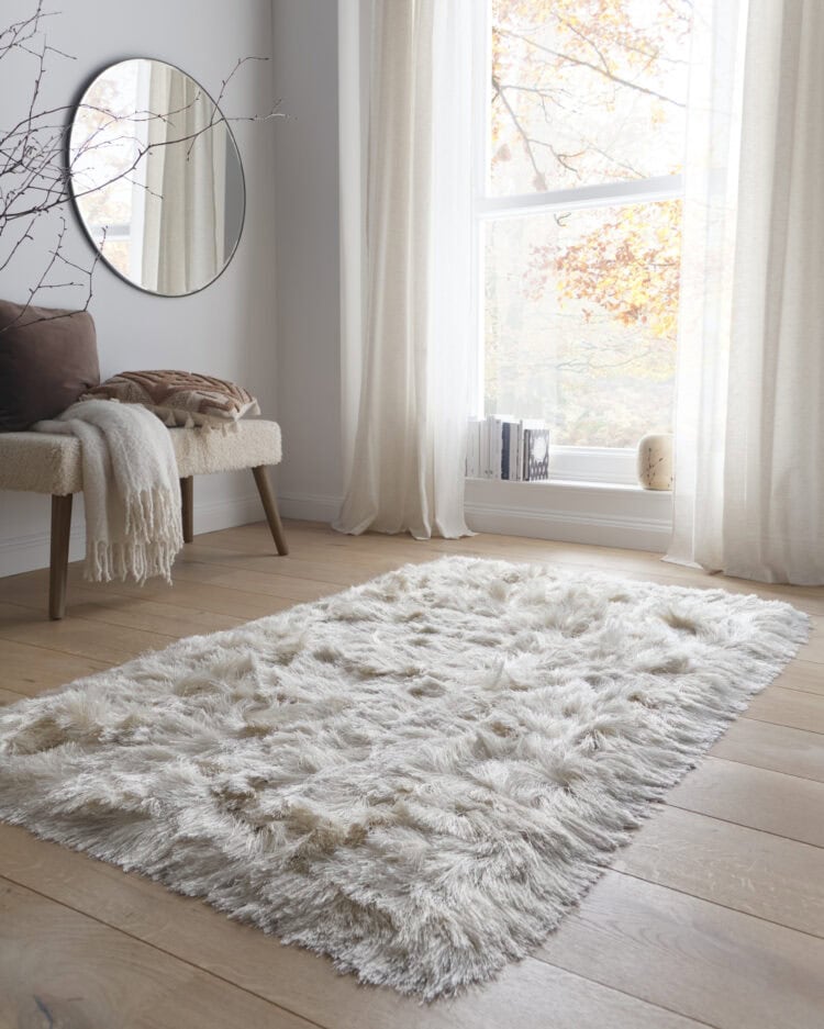 Luxurious ivory shaggy rug in bright living room with large window.