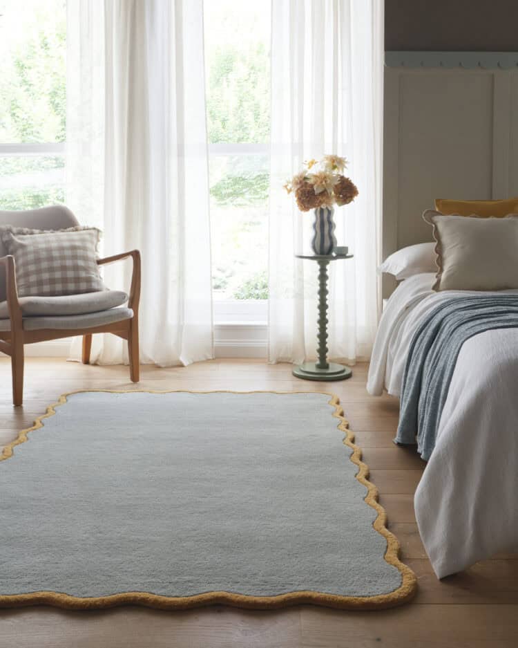 Elegant duck egg scalloped Elsie rug in a bright, airy bedroom setting.
