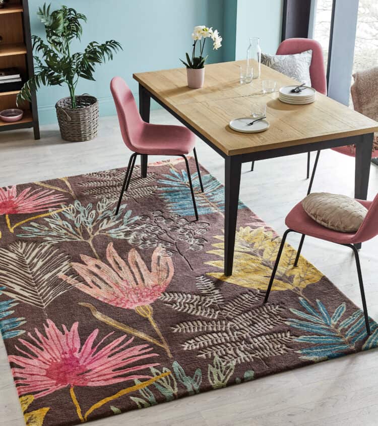 Contemporary dining area with pink chairs and vibrant floral rug.