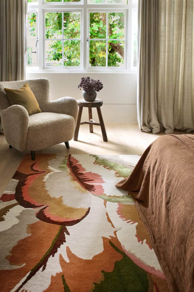 Bright living room with armchair, side table, and large window with curtains.