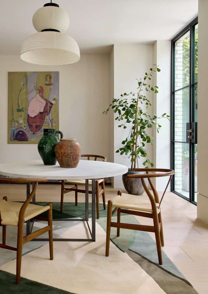 Bright dining room with round table, wooden chairs, and large window.